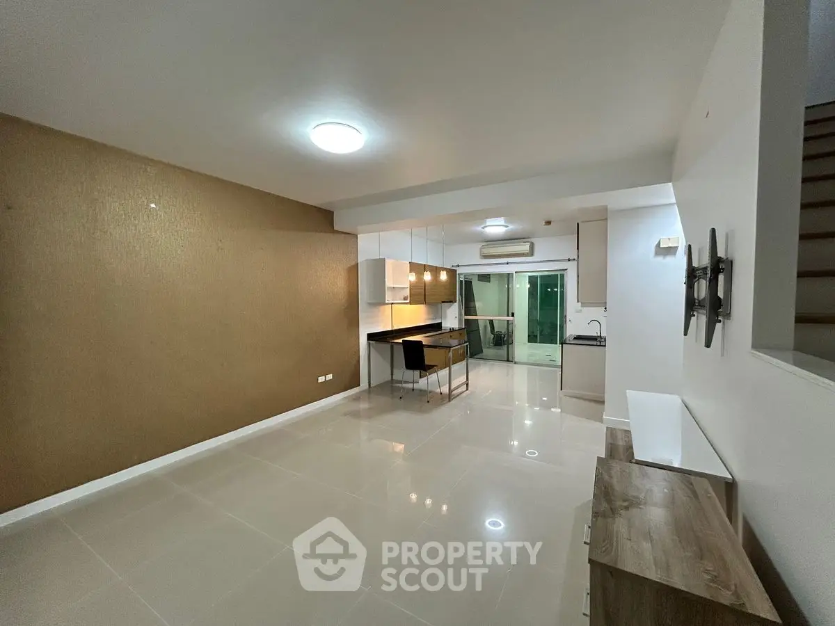 Spacious open-plan living room with modern kitchen and dining area, featuring sleek tile flooring.