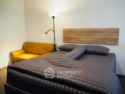 Cozy bedroom with stylish bed and modern lighting, featuring a comfortable yellow sofa for added relaxation.