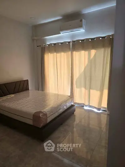 Spacious bedroom with large windows and modern air conditioning unit, perfect for comfortable living.