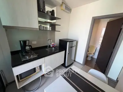 Modern kitchen with sleek appliances and open shelving, adjacent to a compact bathroom.
