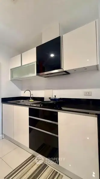 Modern kitchen with sleek black and white cabinetry and built-in appliances.