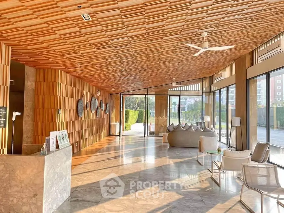 Luxurious modern lobby with wooden ceiling and marble flooring, featuring stylish seating and large windows.