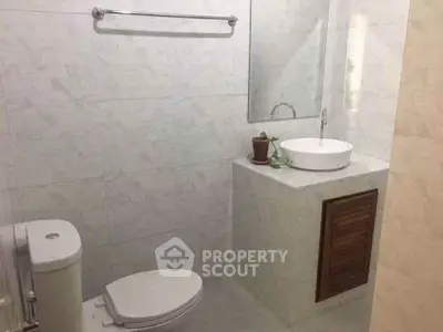 Modern bathroom with sleek fixtures and minimalist design, featuring a wall-mounted sink and toilet.