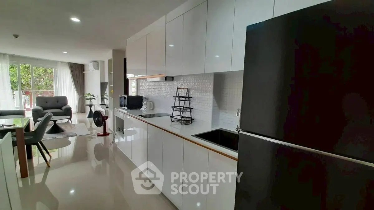 Modern open-layout kitchen with sleek white cabinets and spacious living area.