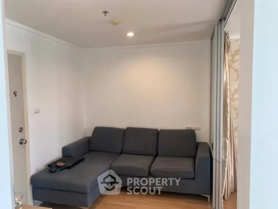 Cozy living room with modern gray sectional sofa and wooden flooring, perfect for relaxation.