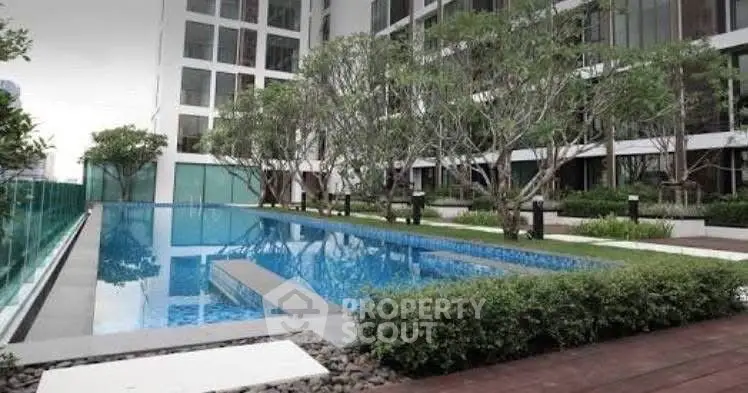 Luxurious residential building with a stunning outdoor pool and lush greenery.
