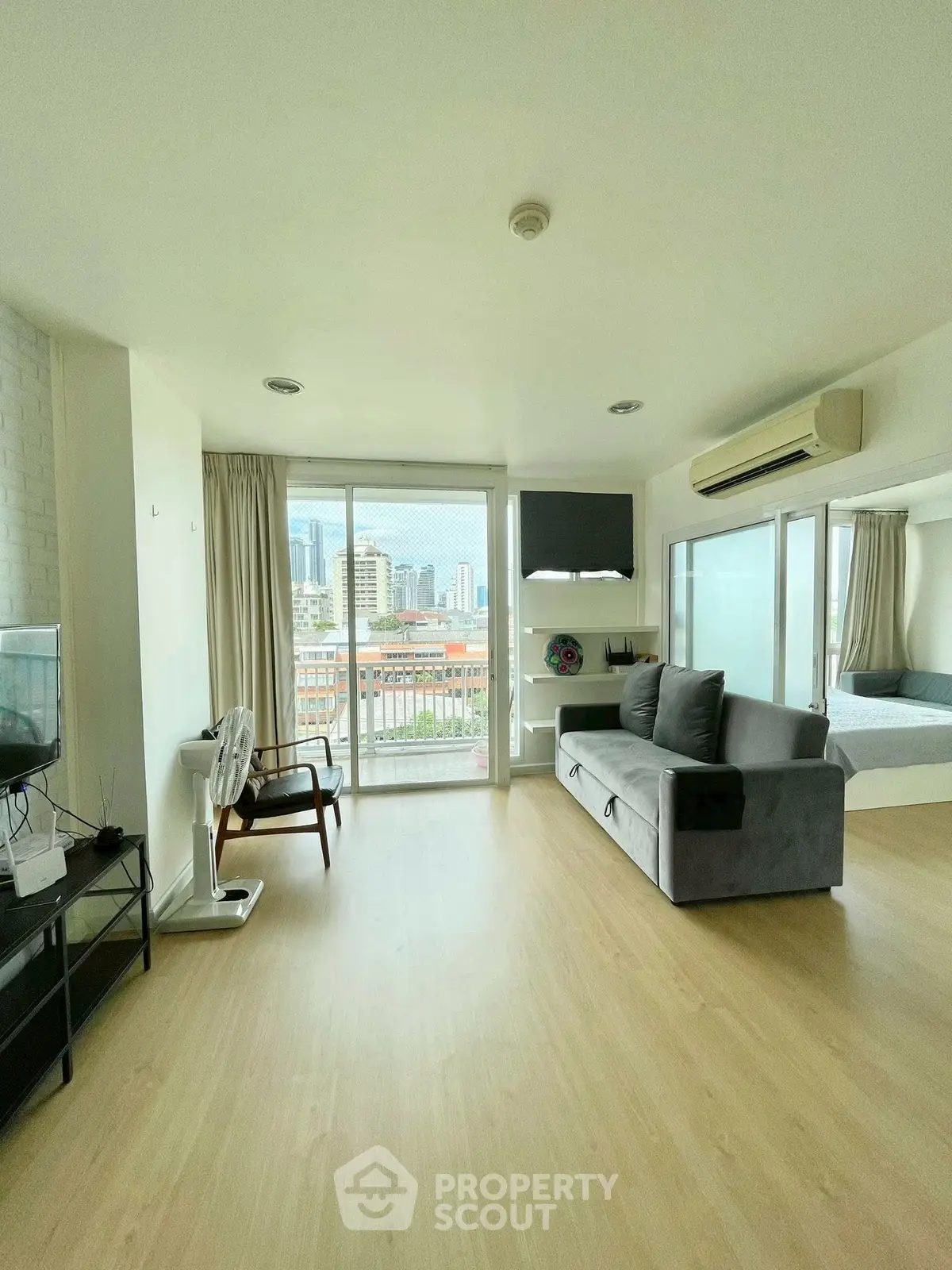 Modern living room with city view, featuring sleek furniture and large windows for natural light.