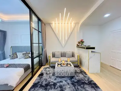 Modern living room with stylish lighting and cozy decor adjacent to a chic bedroom.
