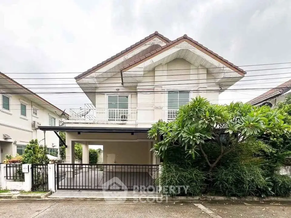 Charming two-story house with a spacious driveway and lush greenery, perfect for family living.