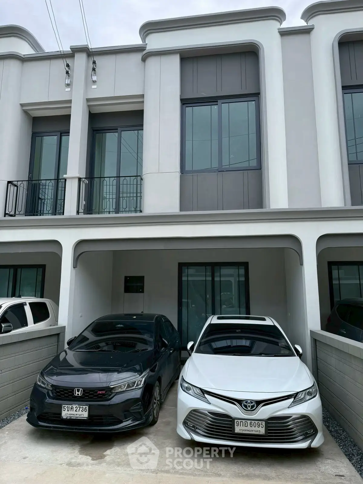 Modern townhouse with two-car parking space in front, showcasing sleek architectural design.