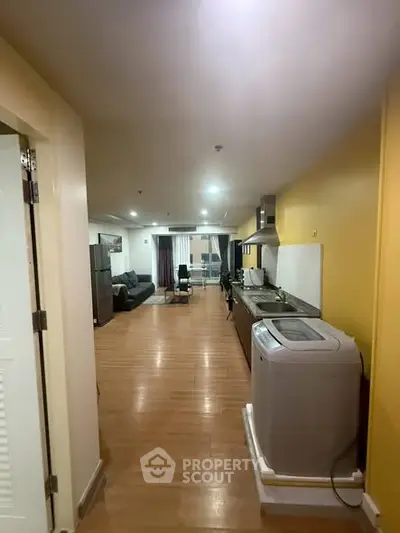Spacious open-plan living area with modern kitchen and washing machine, perfect for urban living.