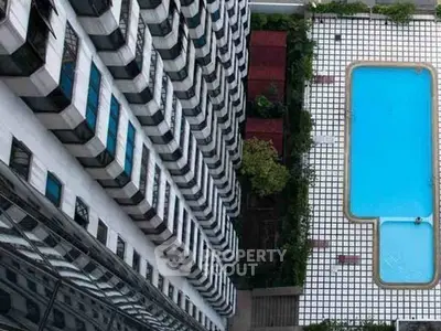 Stunning aerial view of modern building with luxurious swimming pool and landscaped surroundings.