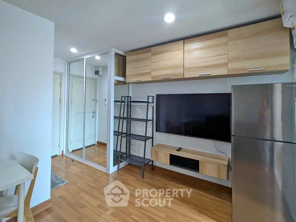 Modern living room with wooden flooring, mirrored closet, and sleek TV setup.