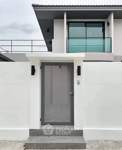 Modern minimalist house entrance with sleek design and glass balcony