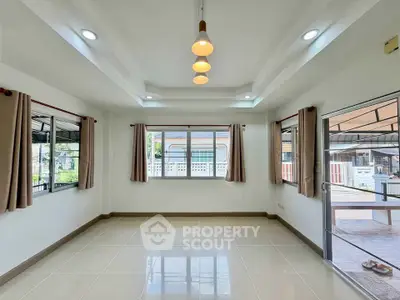 Bright and spacious living room with large windows and modern lighting, perfect for family gatherings.