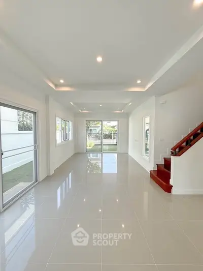 Spacious modern living room with glossy tile flooring and large windows for natural light.