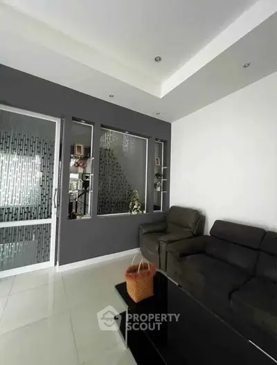 Modern living room with sleek black sofas and stylish glass partition