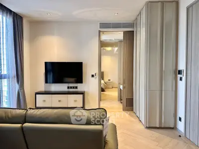 Modern living room with sleek design and wall-mounted TV, leading to a cozy bedroom.