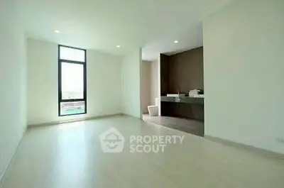 Spacious modern room with large window and sleek bathroom area.