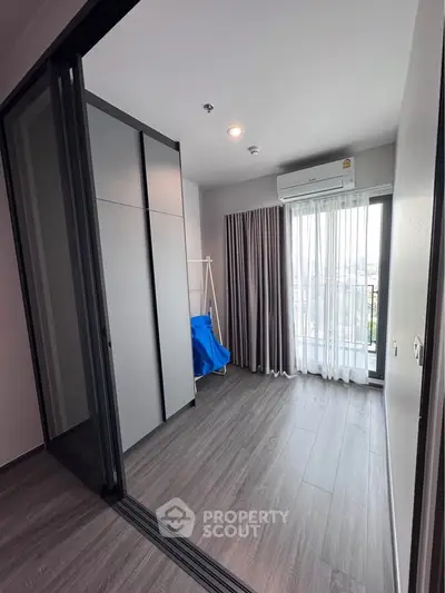 Modern bedroom with large window and sleek flooring in a stylish apartment.