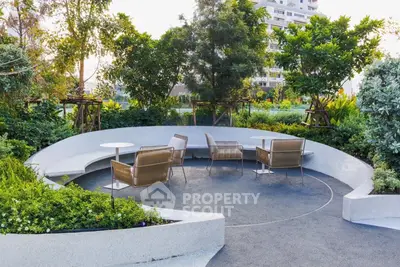 Luxurious garden seating area with modern chairs and lush greenery in a high-end residential complex.