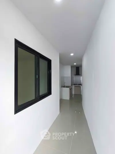 Sleek modern hallway leading to a compact kitchen with glossy tiles and minimalist design.