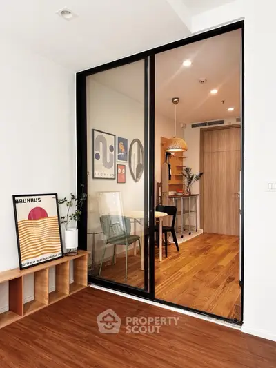 Modern interior with glass partition, wooden flooring, and stylish decor in a cozy apartment.