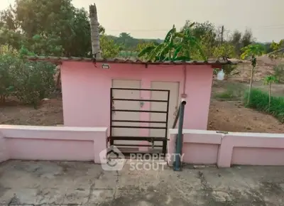 Charming pink rural building with lush greenery, perfect for serene countryside living.