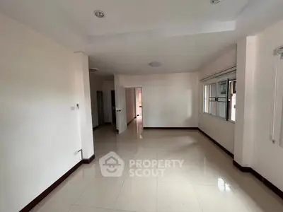 Spacious empty living room with large windows and tiled flooring in modern apartment.