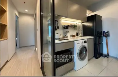 Modern kitchen with sleek appliances and washing machine in compact layout