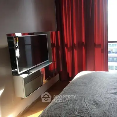 Modern bedroom with wall-mounted TV and red curtains, featuring sleek design and natural light.