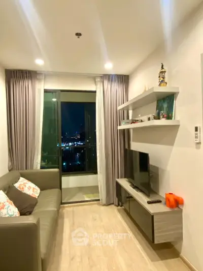 Modern living room with city view, cozy sofa, and sleek TV setup.