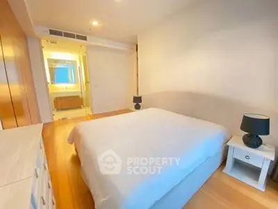 Spacious bedroom with modern decor and ensuite bathroom in luxury apartment.