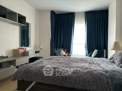 Cozy bedroom with plush bedding and modern decor, featuring a large window with dark curtains.