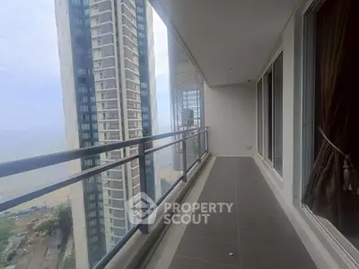 Spacious balcony with stunning city and ocean views in a modern high-rise apartment.