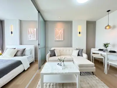 Modern open-plan living room and bedroom with stylish decor and neutral tones.