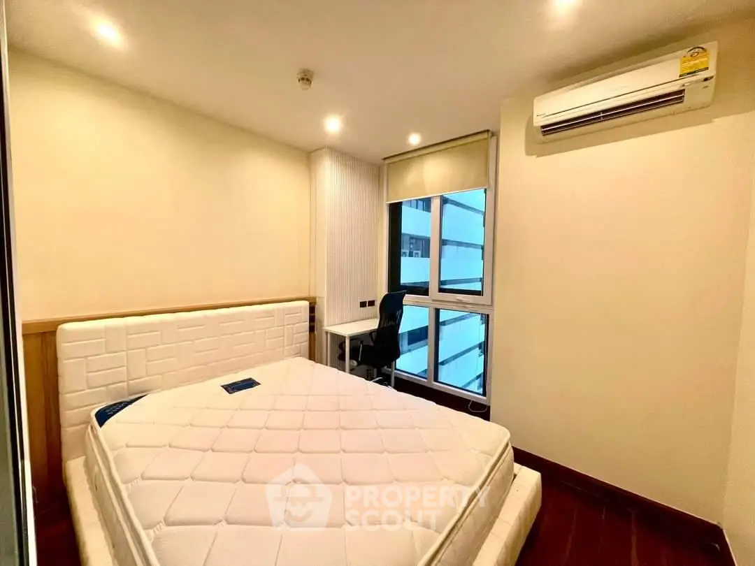 Cozy bedroom with modern air conditioning and large window for natural light.
