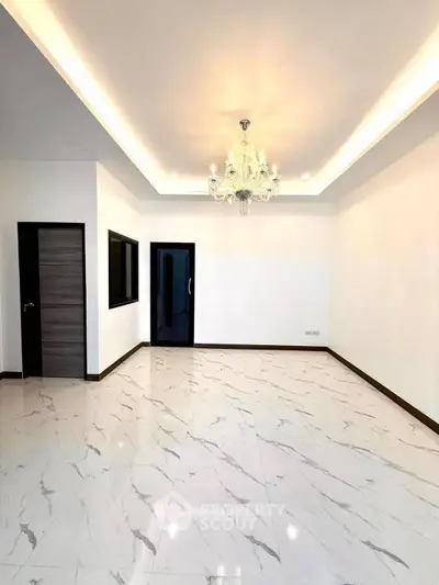 Spacious modern living room with elegant chandelier and marble flooring.