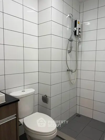 Modern bathroom with sleek white tiles and a compact shower area.