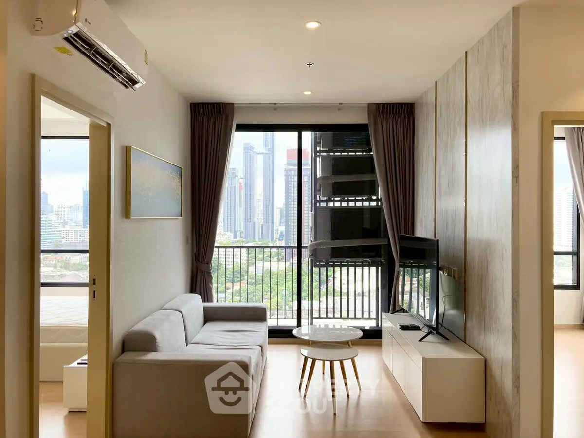Modern living room with city view, featuring sleek furniture and large windows for natural light.