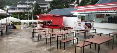 Charming outdoor dining area with modern tables and vibrant red food stall, perfect for social gatherings.