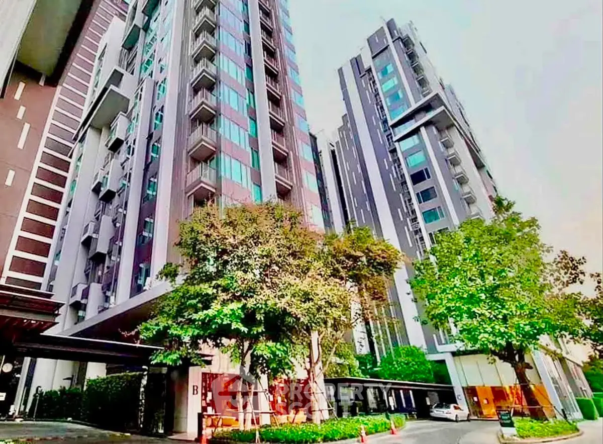 Modern high-rise residential building with lush greenery and sleek architecture.