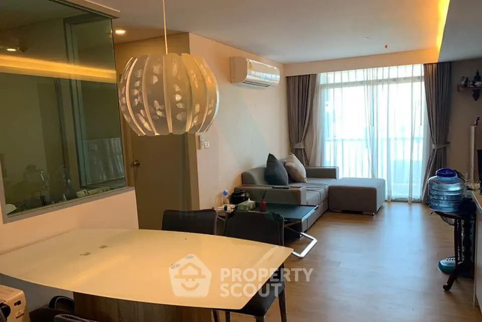 Modern living room with stylish lighting and cozy seating area, featuring a large window for natural light.