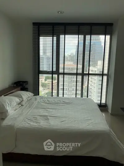 Modern bedroom with large windows offering stunning city views in a high-rise apartment.