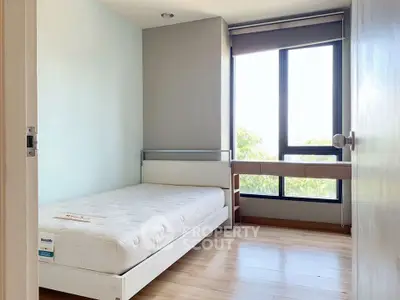 Bright minimalist bedroom with large window and wooden flooring