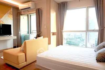 Bright and airy bedroom with large windows offering stunning city views, modern furnishings, and cozy ambiance.