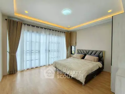 Spacious bedroom with elegant lighting and large windows for natural light.