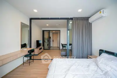 Modern bedroom with stylish decor and open layout leading to living area, featuring sleek furniture and natural light.