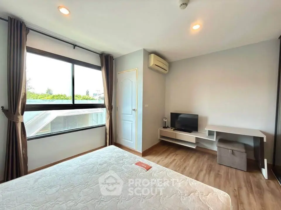 Bright bedroom with large window, modern decor, and wooden flooring