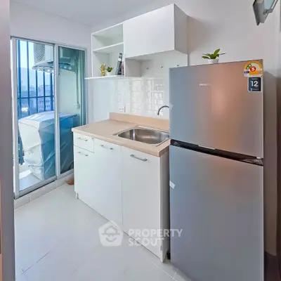 Modern kitchen with sleek cabinetry and stainless steel fridge, featuring a balcony view.